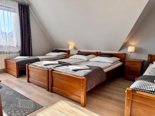 two beds in a bedroom with a attic at Pokoje u Hani - sauna, balia z hydromasażem in Bukowina Tatrzańska