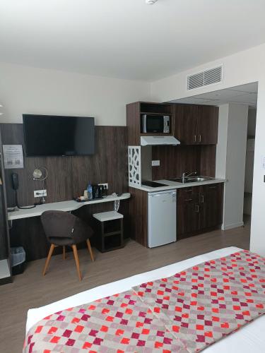 a bedroom with a bed and a desk and a kitchen at Brit Hotel Ploermel - Hotel de l'Hippodrome in Ploërmel