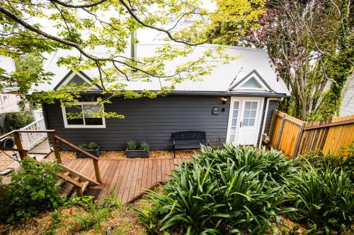 a small black house with a wooden deck at Newly Renovated 100 Year Old Bliss Cottage - Adaline in Katoomba