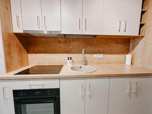 a kitchen with white cabinets and a sink at AGOLL Centru - self checkin in Reşiţa