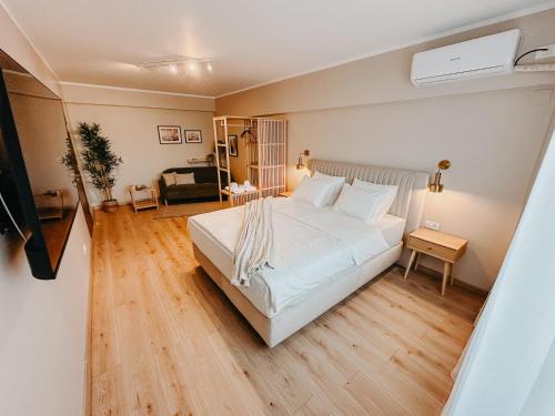 a bedroom with a large white bed and wooden floors at AGOLL Centru - self checkin in Reşiţa