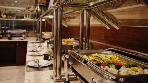 a buffet line with dishes of food in a restaurant at Nozol Royal Inn Hotel in Al Madinah