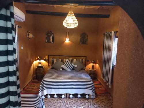 a bedroom with a bed and a chandelier at Riad Tamdakhte in Aït Ben Haddou