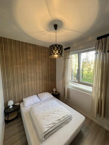 une chambre avec un lit blanc avec une fenêtre dans l'établissement Appartement calme La Bresse animaux admis, à La Bresse