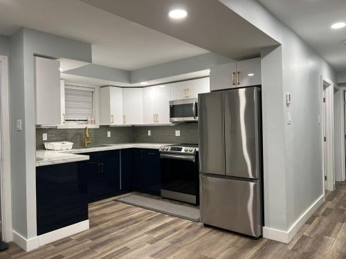 a kitchen with a stainless steel refrigerator and blue cabinets at Yellowknife Down Town Retreat in Yellowknife
