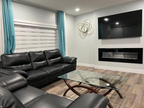 a living room with a black leather couch and a fireplace at Yellowknife Down Town Retreat in Yellowknife