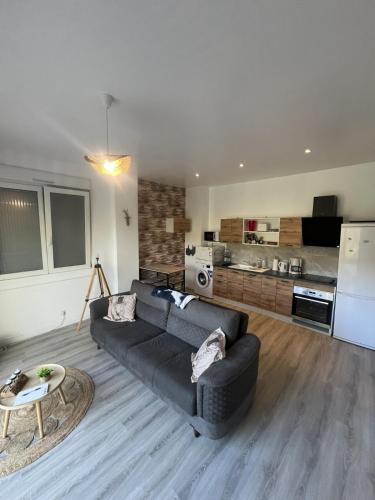 un salon avec un canapé noir et une cuisine dans l'établissement Appartement calme La Bresse animaux admis, à La Bresse