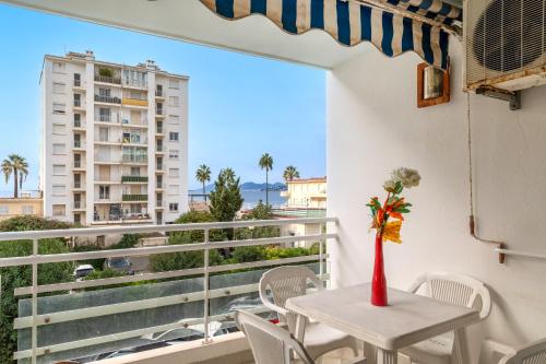une table et des chaises sur un balcon avec vue sur un immeuble dans l'établissement Les Tropiques Bord de mer Juan les pins, à Antibes