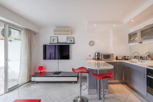 une cuisine avec une table et deux chaises rouges dans l'établissement Les Tropiques Bord de mer Juan les pins, à Antibes