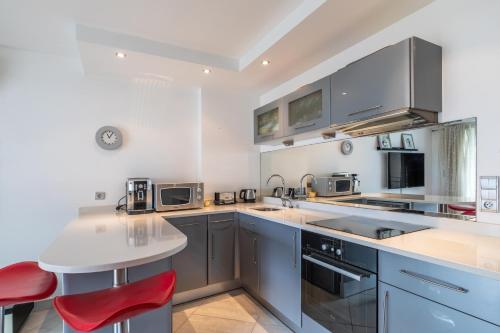 une cuisine équipée d'appareils électroménagers en acier inoxydable et de fauteuils rouges dans l'établissement Les Tropiques Bord de mer Juan les pins, à Antibes