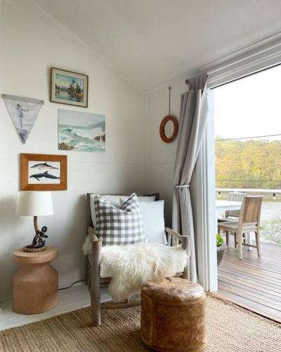 a room with a bed and a balcony with a table at Historic cosy Hawkesbury River cottage in Milson Island