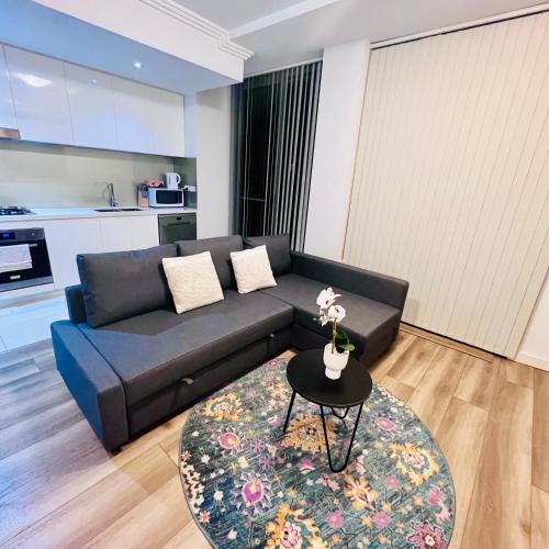 a living room with a black couch and a table at Apartment in Turrella in Sydney
