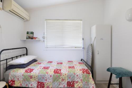 a bedroom with a bed with a quilt on it at Zen Escape Guest House " Location 2" - Zen Garden Tiny Home, Nooky Studio, Chillax Rest in Brisbane