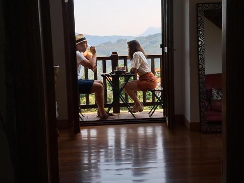 a man and a woman sitting at a table on a balcony at B&B Eguzkitza in Elgeta