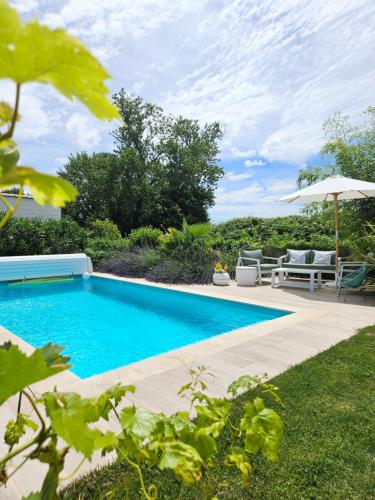 une piscine avec une table, des chaises et un parasol dans l'établissement Le Mâconnais Guest House, à Vinzelles