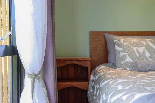 a bedroom with a bed with a curtain next to a window at Kanuka Ridge Lodge in Marahau