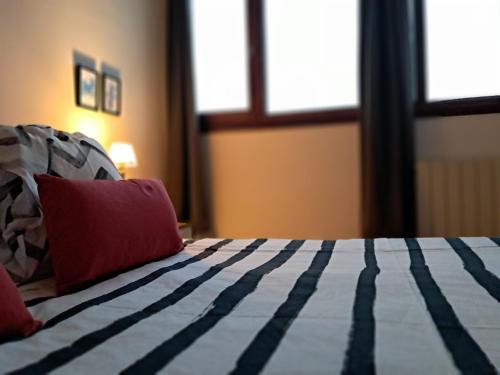 a bedroom with a bed with a red pillow and windows at B&B Eguzkitza in Elgeta