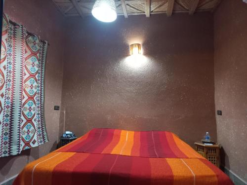 a bed in a room with a colorful blanket at Riad Tamdakhte in Aït Ben Haddou