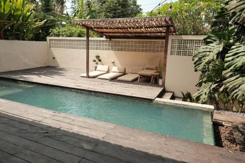 a swimming pool with a pergola and a table and chairs at Little Ripper Boutique Lofts in Tanah Lot