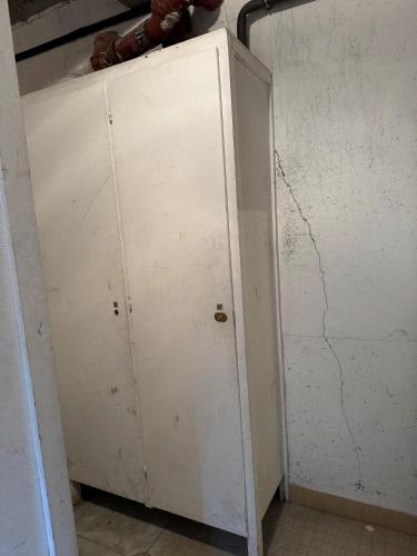 a white cabinet in a room with a cracked wall at Vénosc-Les 2 Alpes , Rez de jardin in Vénosc