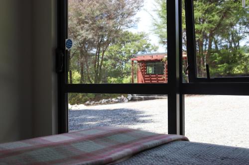 a window with a view of a red bus outside at Kanuka Ridge Lodge in Marahau