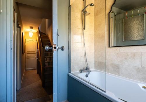 W łazience znajduje się wanna i przeszklony prysznic. w obiekcie Cosy 3 Bedroom Cottage - Central Chipping Norton! w mieście Chipping Norton