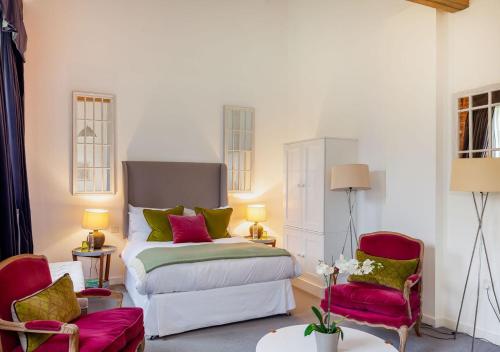 een slaapkamer met een bed en twee stoelen bij Rotheram (Suite) at Bicester Heritage in Bicester