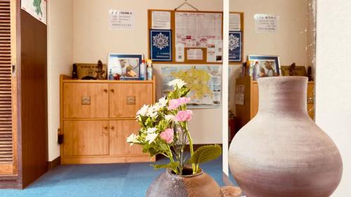 a vase and flowers on a table in a room at 民宿旅館ひろえ1日1組限定 in Kō-jima