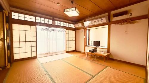 an empty room with a table and a television at 民宿旅館ひろえ1日1組限定 in Kō-jima