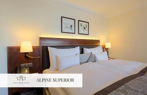 a bedroom with a large bed with white sheets and pillows at Mont Cervin Palace in Zermatt