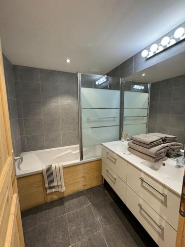 une salle de bain avec une baignoire, un lavabo et un miroir dans l'établissement APT lumineux 8 à 13 pers, au pied des pistes, à La Salle Les Alpes