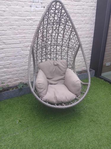 a hanging chair with a pillow in a yard at Eventjes Ertussenuit in Brakel
