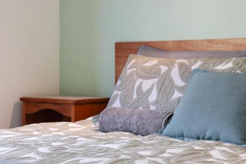 a bed with a blue pillow on top of it at Kanuka Ridge Lodge in Marahau