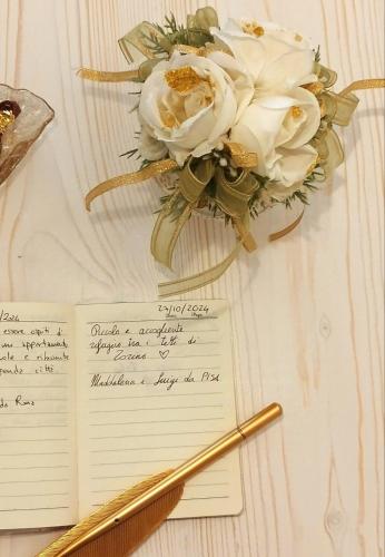 a letter with a pen and flowers on a table at Calin Apartment in Turin