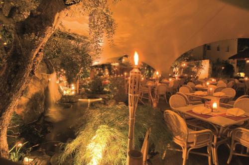 a restaurant with tables and candles and a river at PALMENGARTEN Hotel Gstör in Lagundo