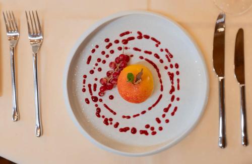 a plate with a fruit on a table with silverware at Hotel de Charme Römerhof in Arbon