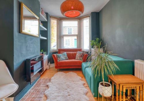 a living room with a green couch and a red chair at Stylish 2BD with Private Garden and Sauna in Oxford