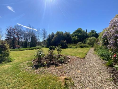 a gravel path in a field with trees and flowers at Parteen A Lax, River House & Gardens in Limerick