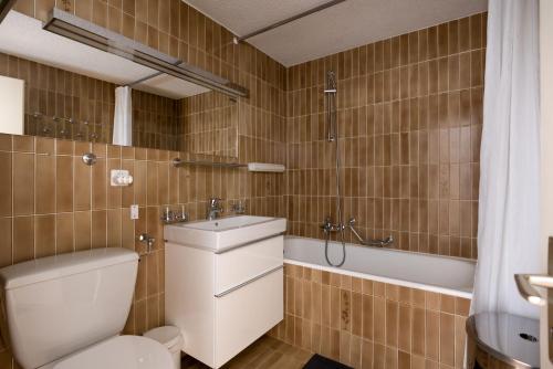 a bathroom with a toilet and a sink and a tub at Apartment Soleil in Le Châble