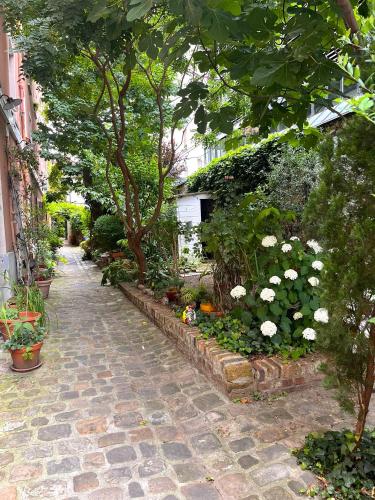un jardin avec des fleurs et des arbres blancs dans une rue dans l'établissement Romantic garden studio, à Paris