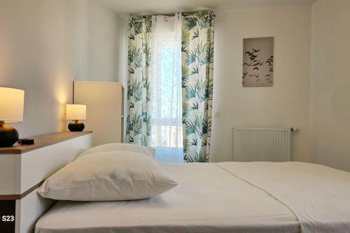 une chambre blanche avec un lit et une fenêtre dans l'établissement Élégant appart à Montpellier Terrasse et parking, à Montpellier