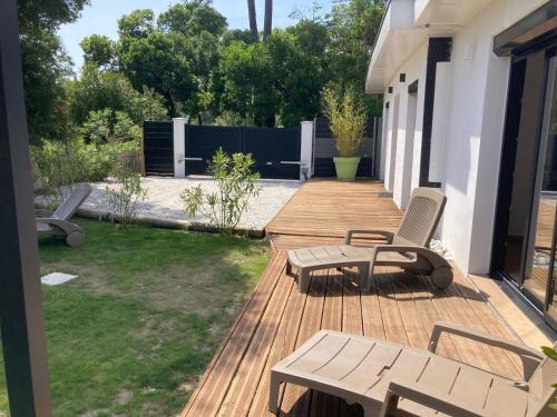 a wooden deck with two chairs and a table at villa bord de mer 400 M de la plage in Labenne