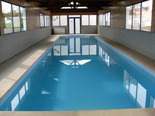 a large swimming pool with blue water in a building at Maison 3 étoiles à 50m mer plages îles nature piscine chauffée jacuzzi privé WIFI in Le Port-des-Barques