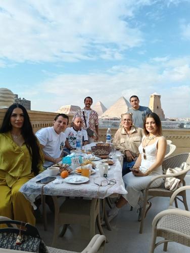 a group of people sitting around a table in front of the pyramids at Mirage pyramids view hotel in Cairo