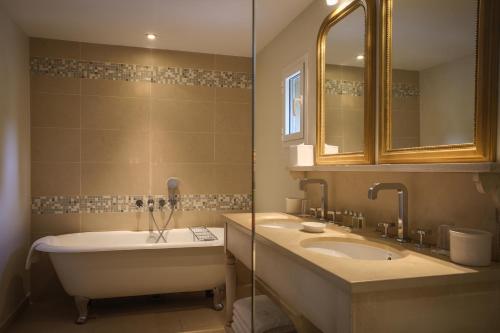 uma casa de banho com 2 lavatórios, uma banheira e um espelho. em Château de Valmer em La Croix-Valmer