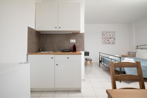 a kitchen with white cabinets and a dining room at Blue Horizon Apartments in Stalida