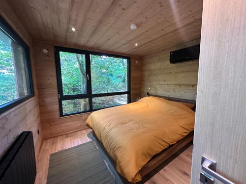 a bedroom in a log cabin with a bed in it at Sous Les Pins in Labaroche