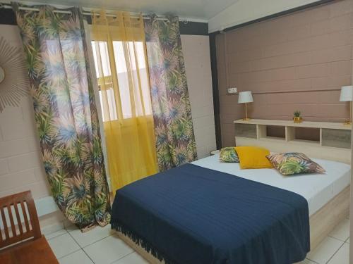 a bedroom with a bed and a yellow curtain at Caz A Mwa in Saint-Joseph
