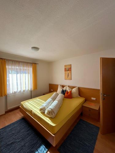 a bedroom with a yellow bed with pillows on it at Appartements Schatzer in Valdaora