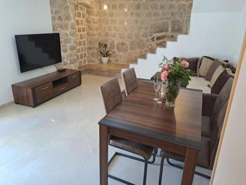Una sala de estar con una mesa de madera y un televisor. en Stara kamena kuca Lustica, en Luštica